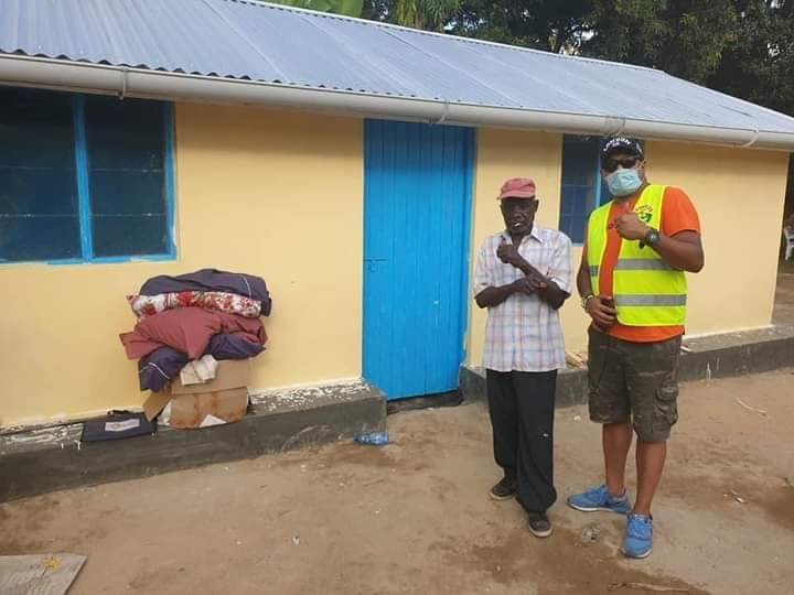 An elderly man standing with a Helping Hands volunteer outside his newly built home