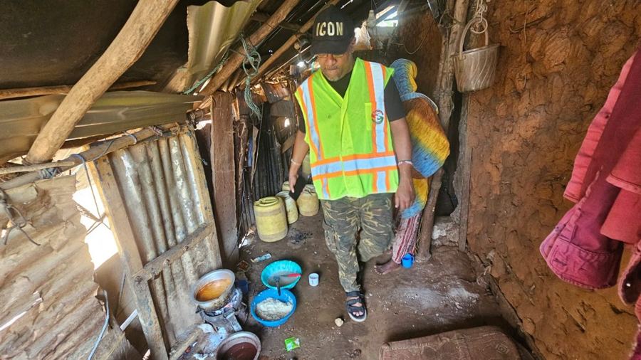 A Helping Hands volunteer visiting a family in a home made of mud walls and scrap metal